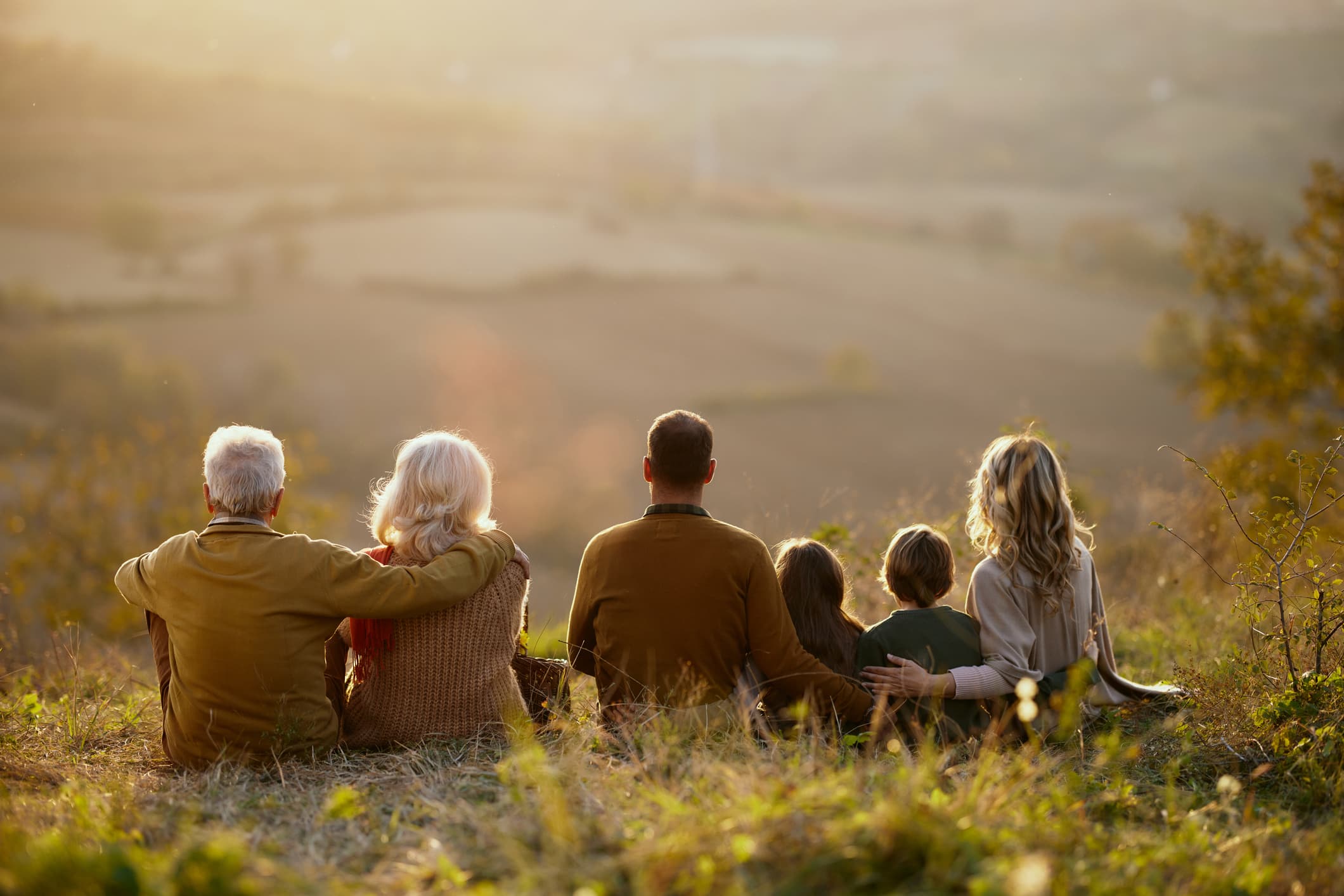 A multigenerational family sitting together at golden hour